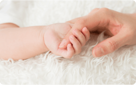 お母さんの指を握る赤ちゃんの手