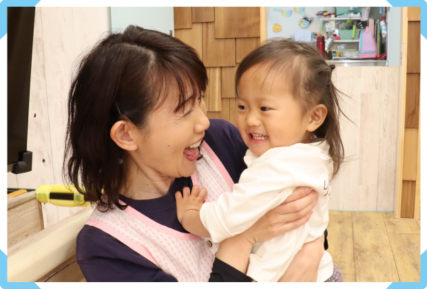 子どもを抱きかかえる保育補助 西山 美奈子